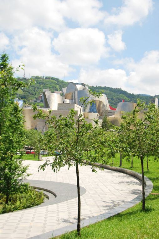 The Guggenheim Museum in Bilbao seen through young trees from the riverside park